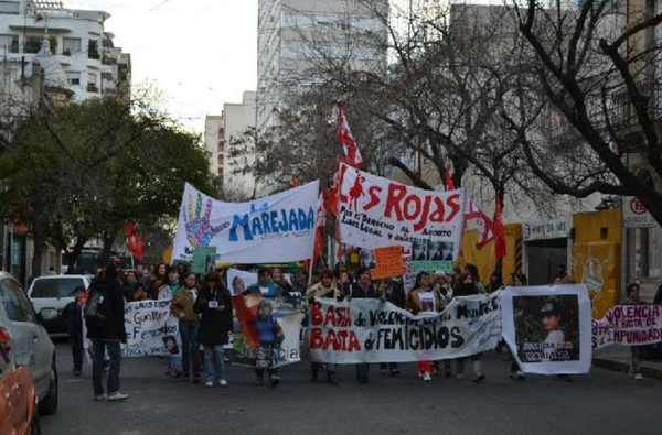 Fotografía de la cabecera de la movilización. Además de banderas de organizaciones sociales y políticas como "Las Rojas" y "La Marejada" pueden verse banderas de familiares y amigues de distintas mujeres y niñas víctimas de femicidio en la ciudad.