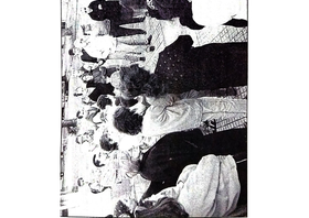 Fotografía publicada en la versión impresa del diario El Día del 9/12/2001. Primer plano de una asamblea de vecines en la esquina de 36 y 115, una persona lee lo que posiblemente sea el petitorio para demandar mayor presencia policial luego de la violación de dos jóvenes en una zona cercana.