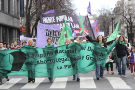 Fotografía de la cabecera de la manifestación por el 28 de septiembre de 2013 en La Plata. En la imagen puede verse la bandera de arrastre de la Campaña Nacional por el Derecho al Aborto Legal, Seguro y Gratuito La Plata y, detrás, de la Campaña Nacional contra las Violencias hacia las Mujeres y del FPDS.