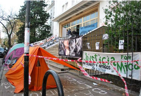 Fotografía acampe frente a la fiscalía. En la imagen pueden verse carpas, banderas con consignas y pintadas en el asfalto