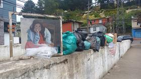 Emplazamiento de una copia de la pintura "Mujer del pueblo" de Anibal Pinto. La intervención el día en qué pasa la basura (lxs vecinxs colocan las bolsas de basura al lado).