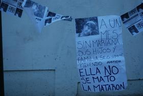Fotografía de girnalda colgada en la manifestación a un mes del asesinato de Mariana Condorí en el barrio Los Hornos. En la fotografía puede verse una cartulina con una foto de Mariana en blanco y negro con la frase "A un mes sin Mariana sus hijos y familia seguimos pidiendo justicia. Ella no se mató, la mataron".
