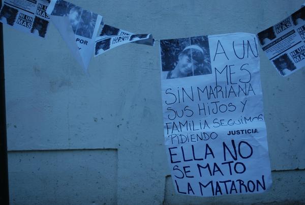 Fotografía de girnalda colgada en la manifestación a un mes del asesinato de Mariana Condorí en el barrio Los Hornos. En la fotografía puede verse una cartulina con una foto de Mariana en blanco y negro con la frase "A un mes sin Mariana sus hijos y familia seguimos pidiendo justicia. Ella no se mató, la mataron".