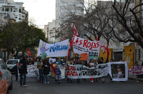 Fotografía de la cabecera de la movilización. Además de banderas de organizaciones sociales y políticas como "Las Rojas" y "La Marejada" pueden verse banderas de familiares y amigues de distintas mujeres y niñas víctimas de femicidio en la ciudad.